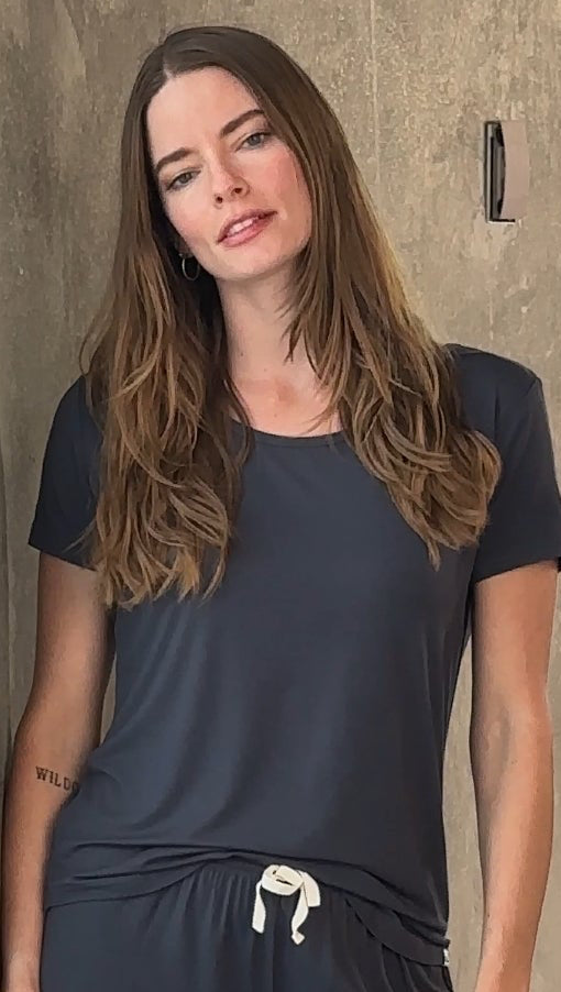 Woman wearing a dark blue bamboo T-shirt and shorts lounge set against a neutral background